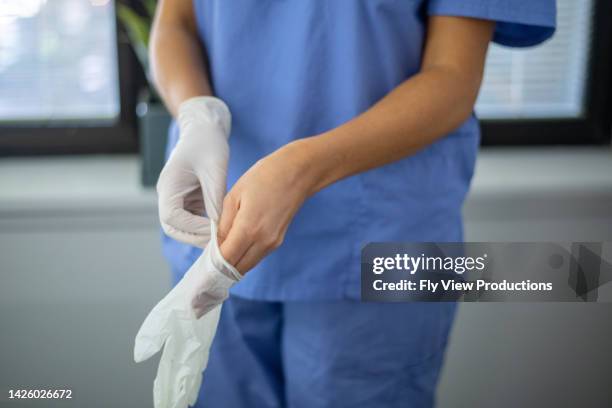 photograph of an unrecognizable nurse putting on surgical gloves - luva de borracha imagens e fotografias de stock