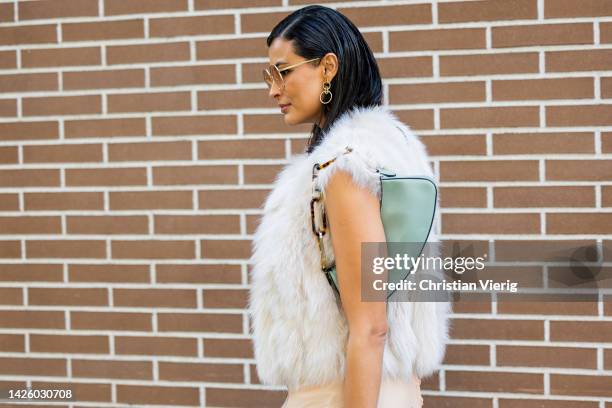 Guest wears faux fur vest, two tone dress, earrings, mint green bag, sunglasses outside Fendi during the Milan Fashion Week - Womenswear...