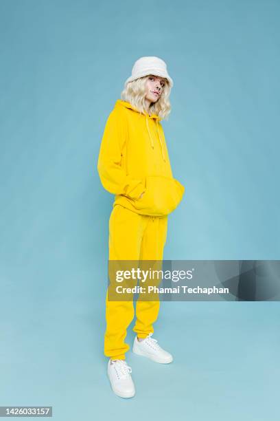fashionable woman wearing yellow track suit - blauwe schoen stockfoto's en -beelden
