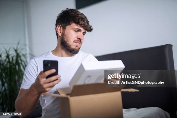 confused man opening a messed up delivered package. - unhappy customer stock pictures, royalty-free photos & images