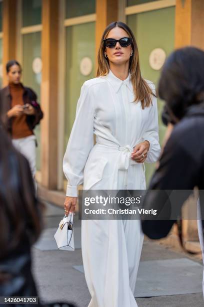 Alessandra Ambrosio wears white high waisted pleated pants, blouse, white bag, brown platform sandals, sunglasses outside Alberta Ferretti during the...