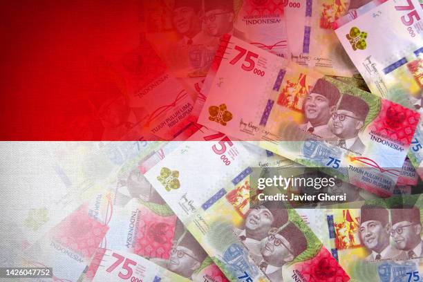 indonesian rupiah cash banknotes and indonesian flag - indonesia flag stock pictures, royalty-free photos & images