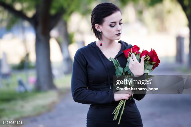 teenage girl holding flowers in a cemetery. - funeral grief flowers stock-fotos und bilder