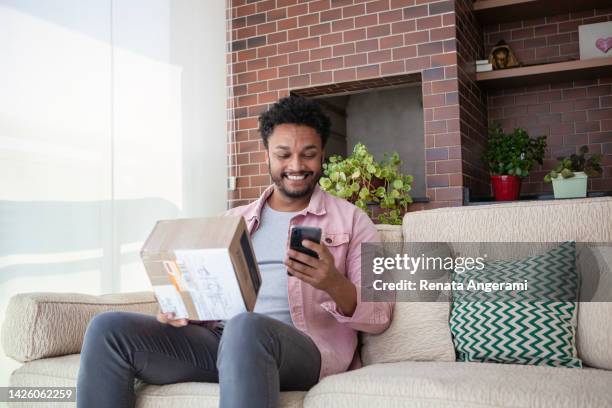 african american young man shopping online at home - online shopping opening package stock pictures, royalty-free photos & images