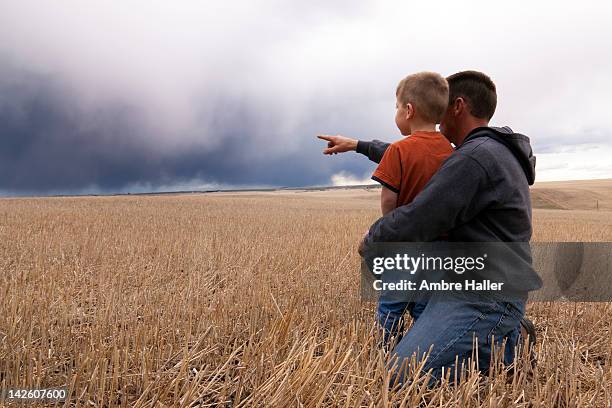 father and son watching storm coming in - storm cloud stock pictures, royalty-free photos & images