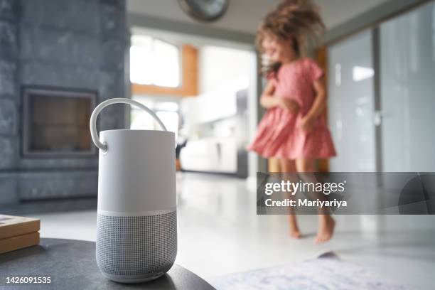 a girl dances against the background of a remote wi-fi smart speaker. - bluetooth photos et images de collection