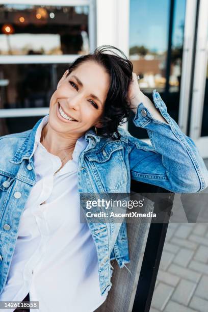 woman in casual clothing relaxes in urban setting - jean jacket stock pictures, royalty-free photos & images