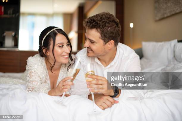 casal recém-casado brindando flautas de champanhe na cama - adorno floral - fotografias e filmes do acervo