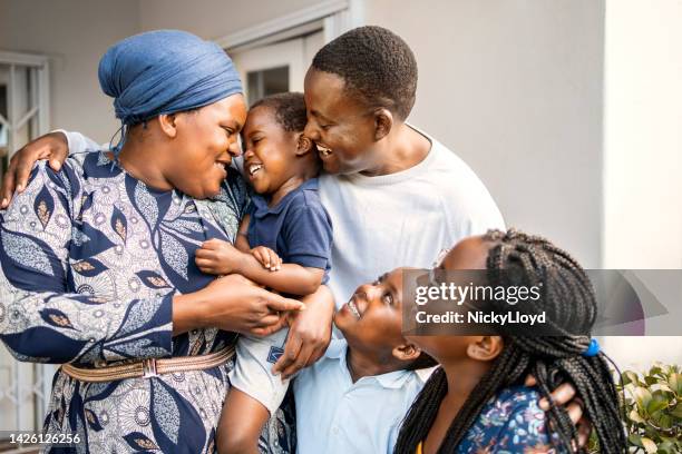 famiglia amorevole in piedi insieme fuori dalla loro casa - popolo di discendenza africana foto e immagini stock