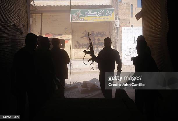 Rebels of the Free Syrian Army take cover in the market square from exploding shells fired by government tanks that have advanced into Saraquib city...