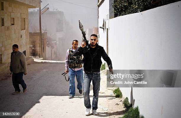 Rebels of the Free Syrian Army take cover from exploding shells fired by government tanks that have advanced into Saraquib city on April 9, 2012 in...