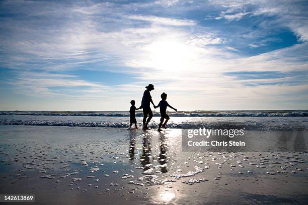 grandmother and grandsons walkng on the beach - grandmother and grandchild beach fotografías e imágenes de stock