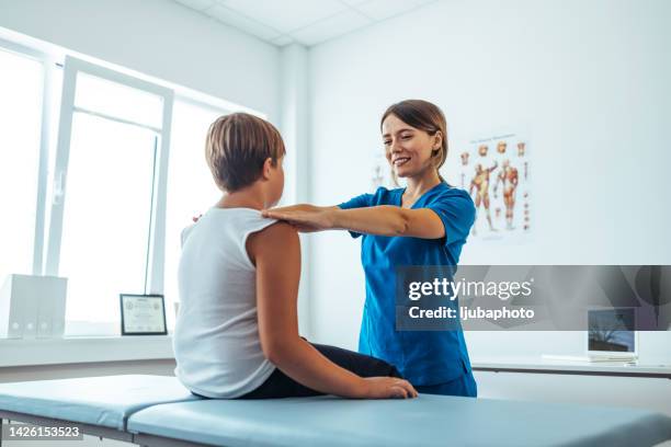 teenage boy sitting on massage table and getting physical therapy - competitive examination exam stock pictures, royalty-free photos & images