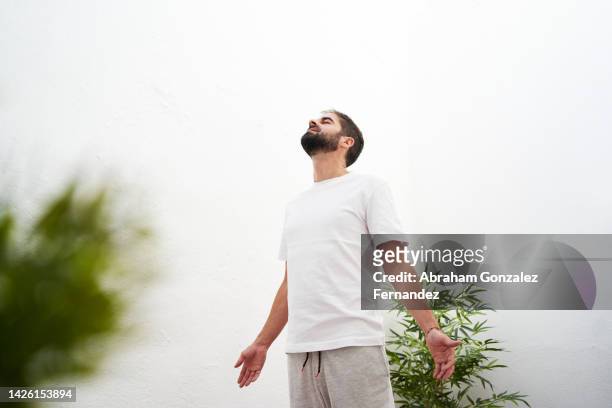 a man on the rooftop of his apartment getting fresh air while doing relaxation exercises - fresh air breathing stockfoto's en -beelden