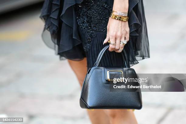 Elizabeth Sulcer wears a black ruffled tulle/ embroidered pearls / sleeveless / short skirt, gold and diamond Love bracelets from Cartier, rings, a...