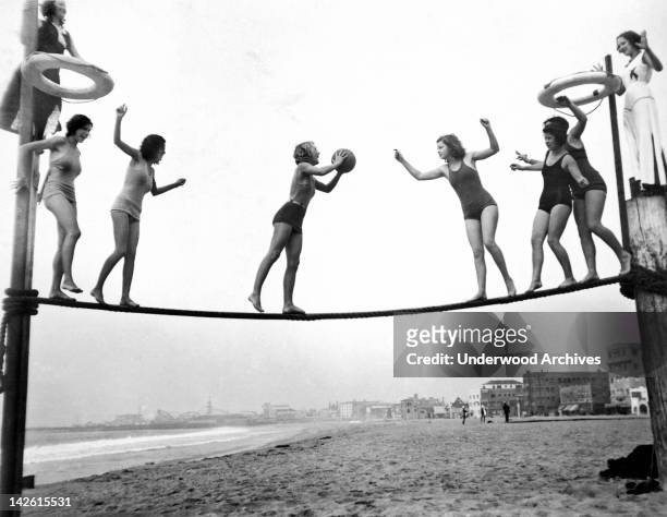 Members of the Venice Beach Girls Dare Club, a group of bathing beauties who do a new stunt every Sunday, playing tightrope basketball, Venice,...