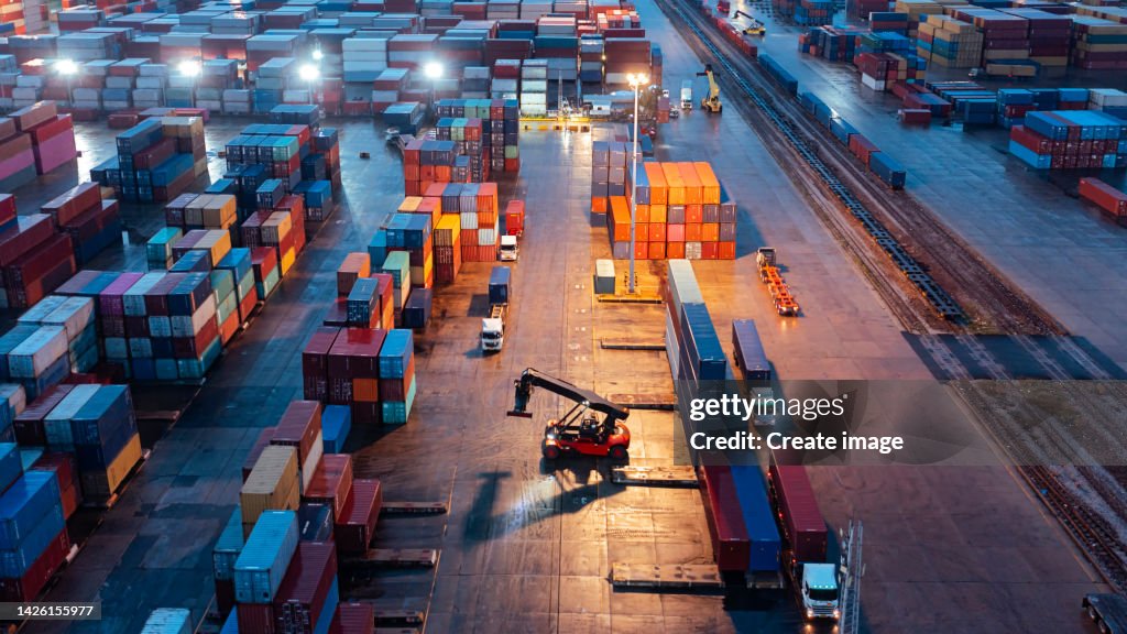 Aerial view forklift handling container load to container truck at container warehouse for business logistics, import export, shipping or freight transportation.