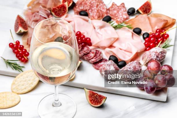 two glasses of white wine or prosecco with appetizers salami ham olives berries. aperitif food - charcuterie stockfoto's en -beelden