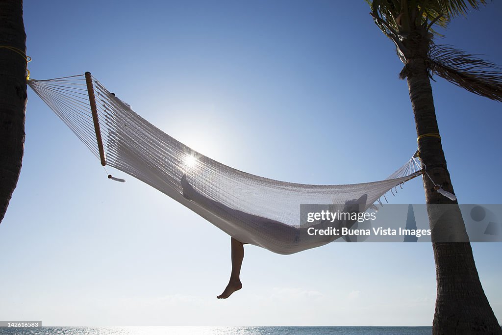 Woman relaxing in a hammock on the beach