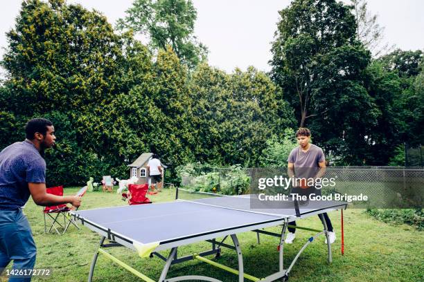 brothers playing table tennis in back yard during weekend - men's table tennis stock pictures, royalty-free photos & images