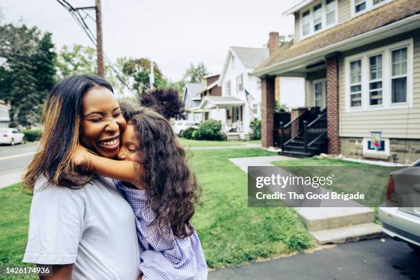 girl embracing mother in front yard - mittelstand stock-fotos und bilder