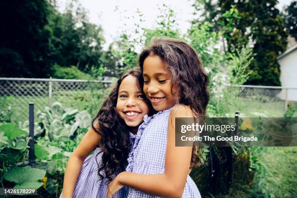 portrait of happy girl embracing sister in garden - girl 6 7 stock pictures, royalty-free photos & images