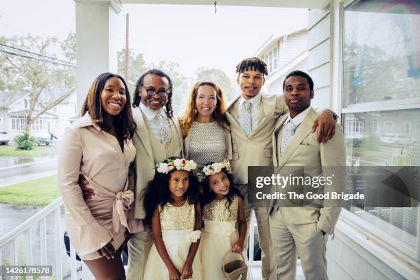 portrait of mature bride and groom standing on porch with family - blended family stockfoto's en -beelden