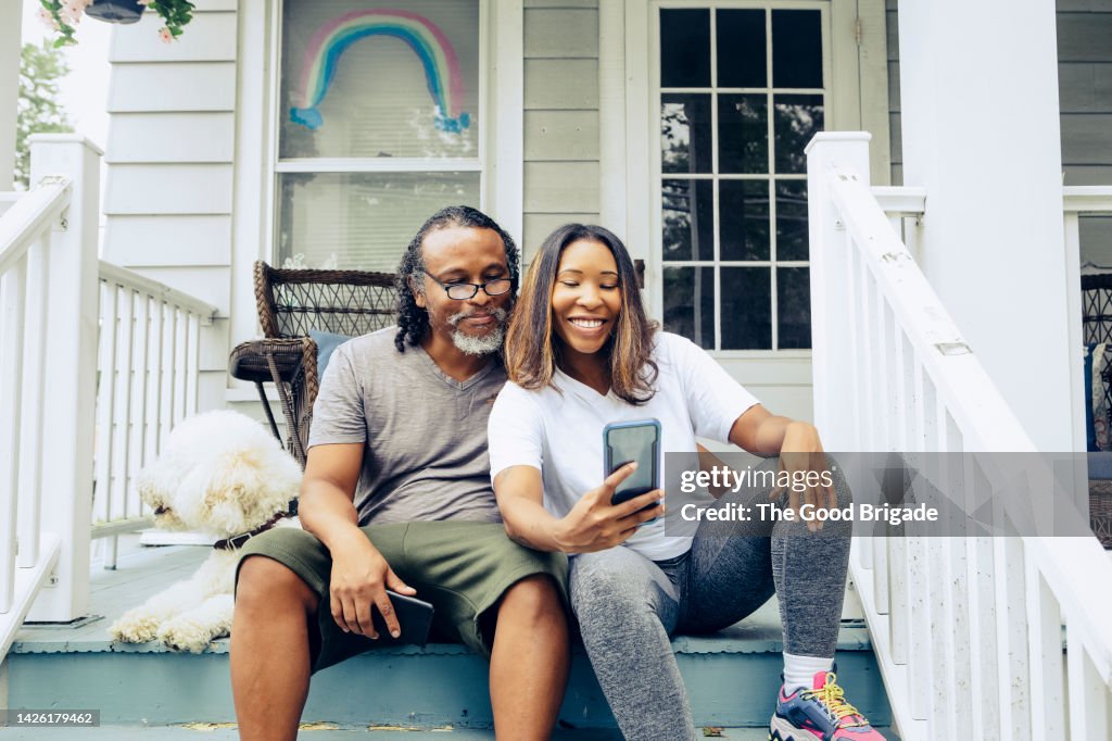Young woman taking selfie with father on front porch at home