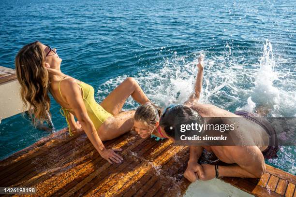 family playing in sea - family yacht stock pictures, royalty-free photos & images