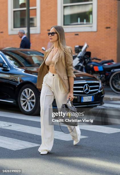 Ginta Kubiliute wears Fendi camel blazer, beige cutout top, white pants, off white shoes, stone grey Hermes bag, Saint Laurent sunglasses, braid...