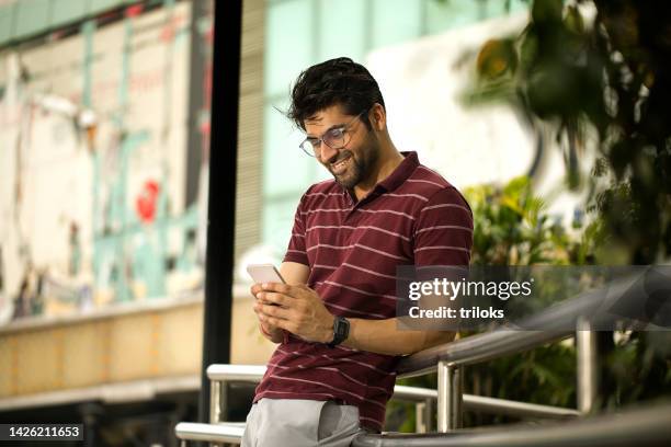 man using mobile phone outdoors in city - phone leaning stock pictures, royalty-free photos & images