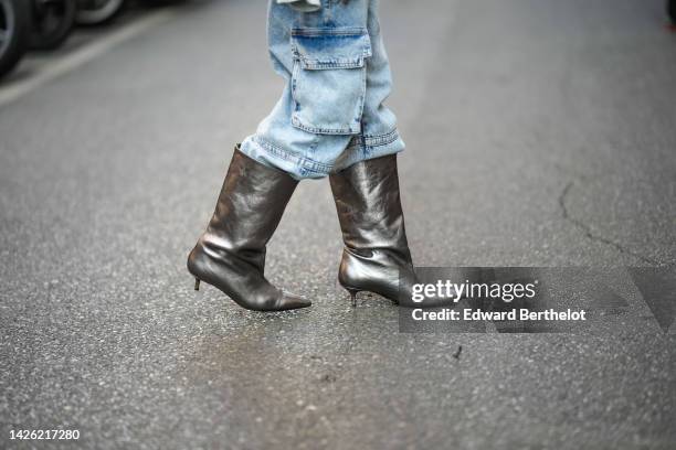 Guest wears blue faded denim cargo pants, silver dark shiny leather pointed heels knees boots , outside Alberta Ferretti, during the Milan Fashion...