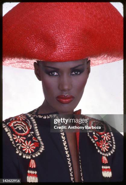 Portrait of Jamaican-born model, singer, and actress Grace Jones as she wears a bright red hat and multi-colored top, New York, New York, late...