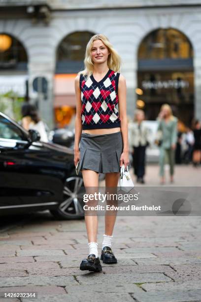 Guest wears a navy blue with white jacquard and red heart print pattern V-neck / sleeveless wool pullover, a gray pleated short skirt, white socks,...