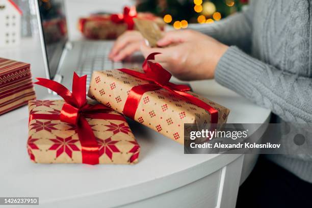 winter holidays, online shopping at home. female hands on the laptop with gifts and blurred bokeh lights - boxing day shopping in winter stockfoto's en -beelden