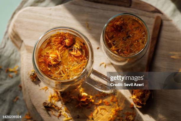 calendula herbal tea in two glass cups on wooden tray - calendula stockfoto's en -beelden