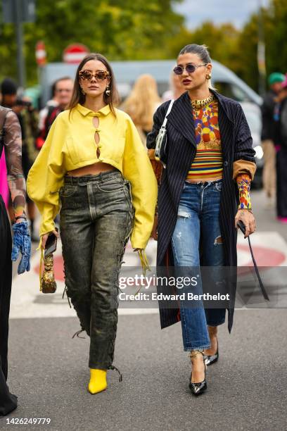 Mina Habchi wears brown leopard print pattern sunglasses, gold earrings, a yellow puffy long sleeves / buttoned / cropped top, black and yellow faded...