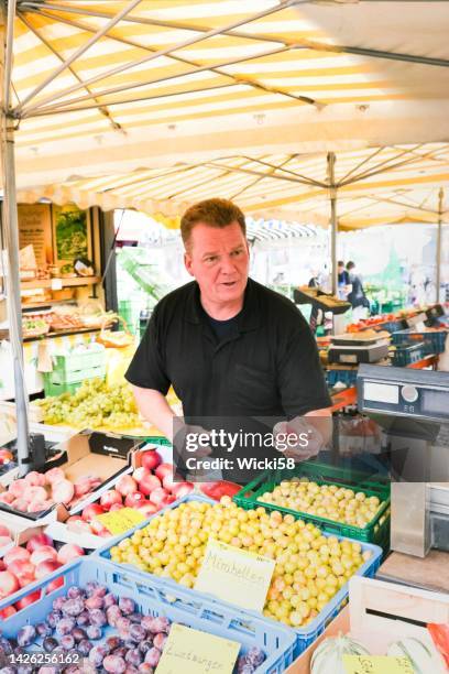 fruit vendor sells fresh peaches and plums - mirabelle plum stock pictures, royalty-free photos & images