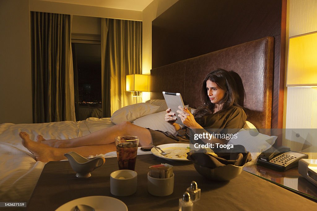 Woman reading digital tablet in bed