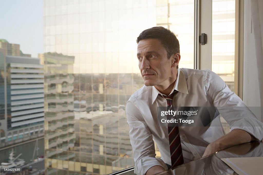 Businessman looking out window to city
