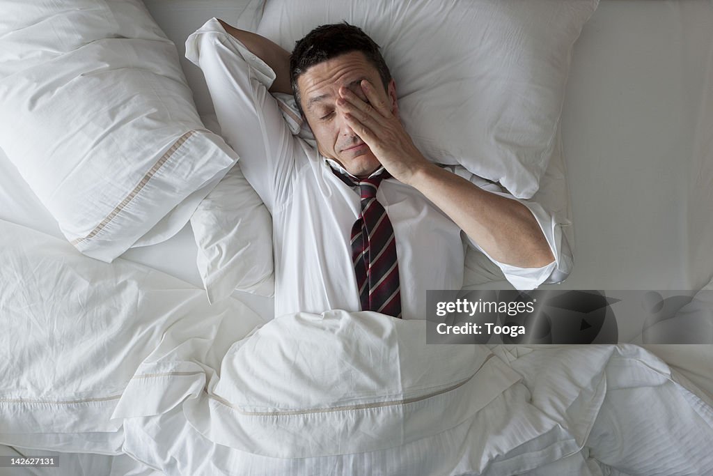 Businessman in bed with clothes on