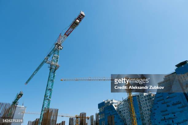 a high-rise multi-storey building or residential building under construction. construction site with cranes on a blue sky background. - tyumen stock pictures, royalty-free photos & images