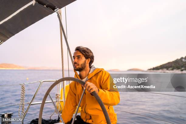 junger mann steuert segelboot auf see - adria tour stock-fotos und bilder