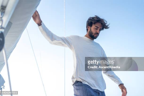 young man prepares sail on mast at sea - long sleeve t shirt stock pictures, royalty-free photos & images