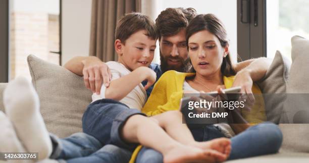 tablet, subscription and family streaming a movie as father relaxing with his wife and child at home on the sofa. portrait of mother, dad and kid watching tv, film or movies on the couch together - content stock pictures, royalty-free photos & images