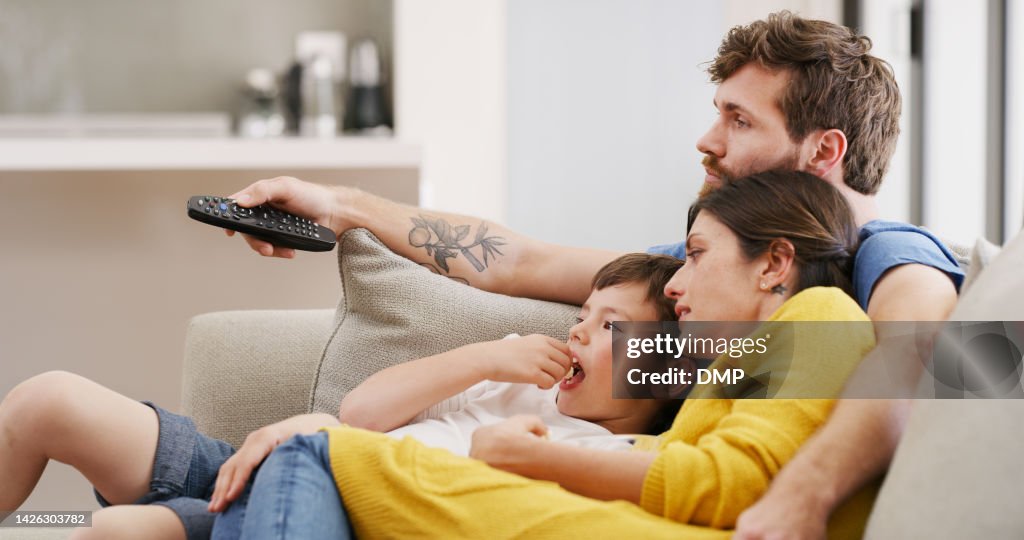 Family popcorn, watching tv and relax in living room for movie, streaming film on subscription service and news on television. Mother, father and kid eating food on the sofa with a film in home
