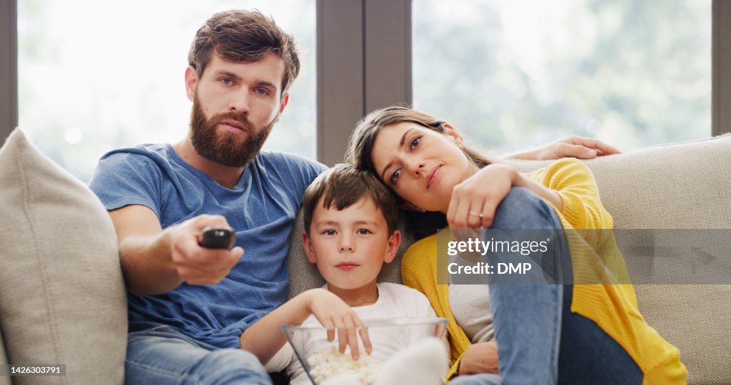 Family movie time, eating popcorn on sofa in living room or lounge at home. Relax, love or bonding with caring father, mother and son together on tv, streaming film or video on couch with remote.