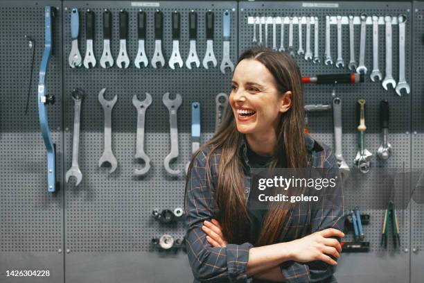 giovane donna sorridente seduta sul banco da lavoro in officina - metal grate foto e immagini stock