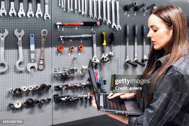 young woman looking at laptop in workshop - tool rack stock pictures, royalty-free photos & images