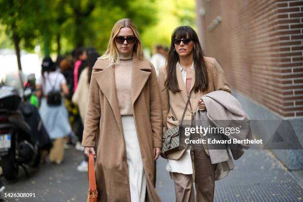 Guest wears black sunglasses, a beige wool turtleneck pullover, a beige long wool coat, a white knees skirt, an orange shiny leather handbag, a guest...